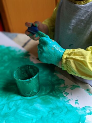 Une main d'enfant couverte de peinture turquoise, atelier peinture